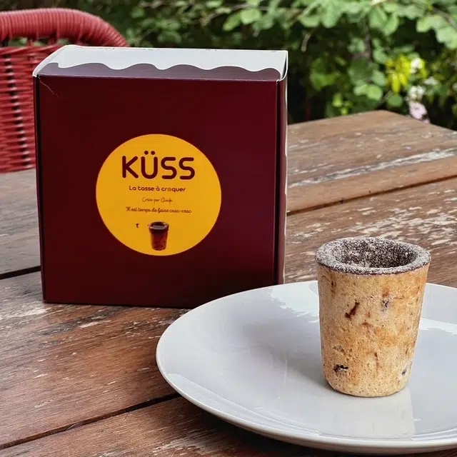 Photo de la boîte de tasses Küss et d'une tasse, seule, au milieu d'une assiette blanche