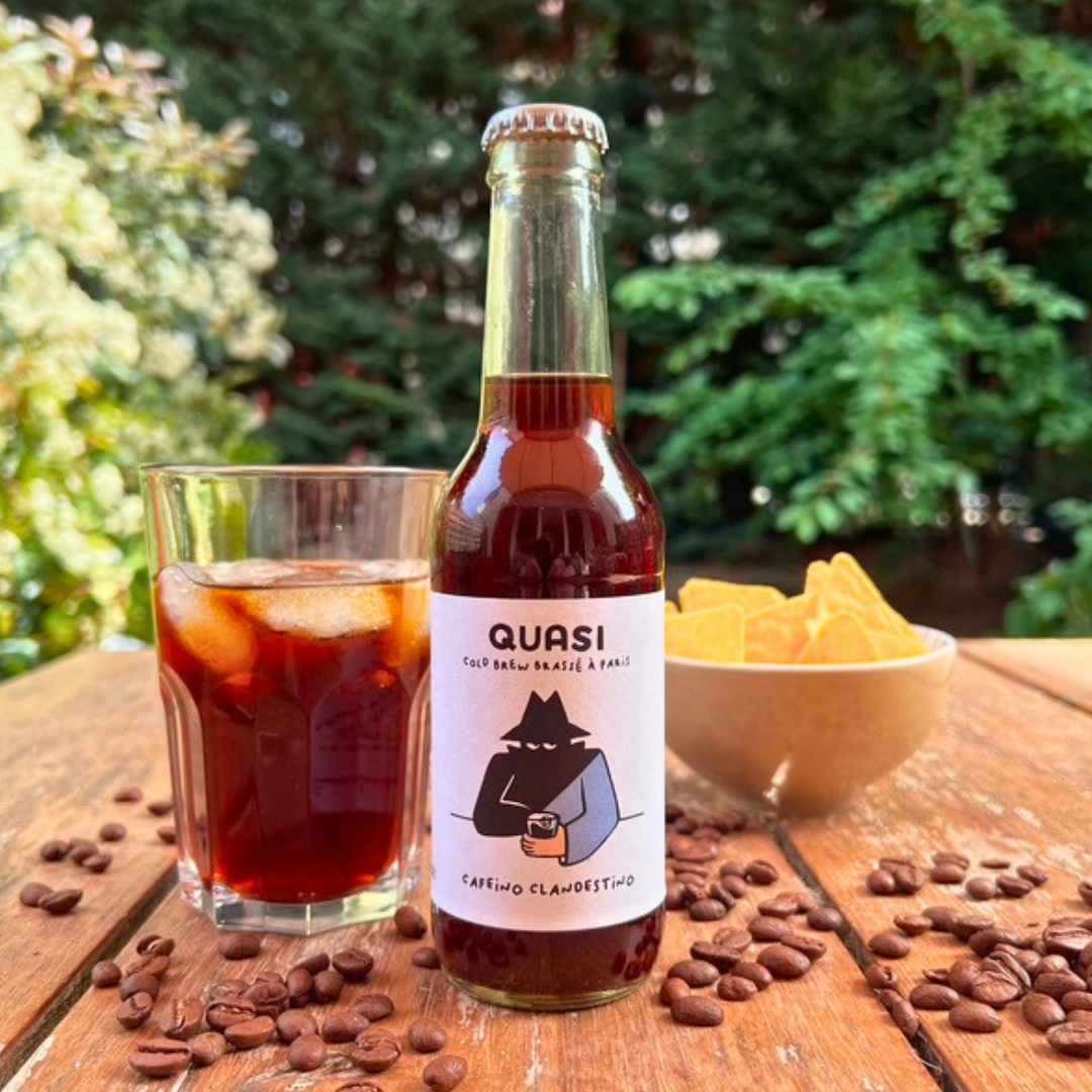 Photo d'une bouteille de cold brew avec un verre rempli de glaçons, avec des chips en fond
